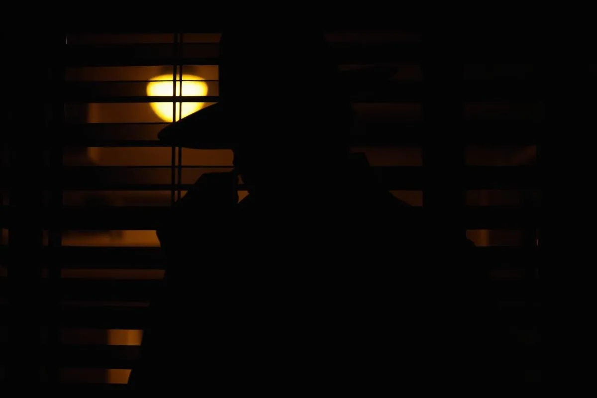 Detektiv beobachtet durch Jalousien bei Nacht
