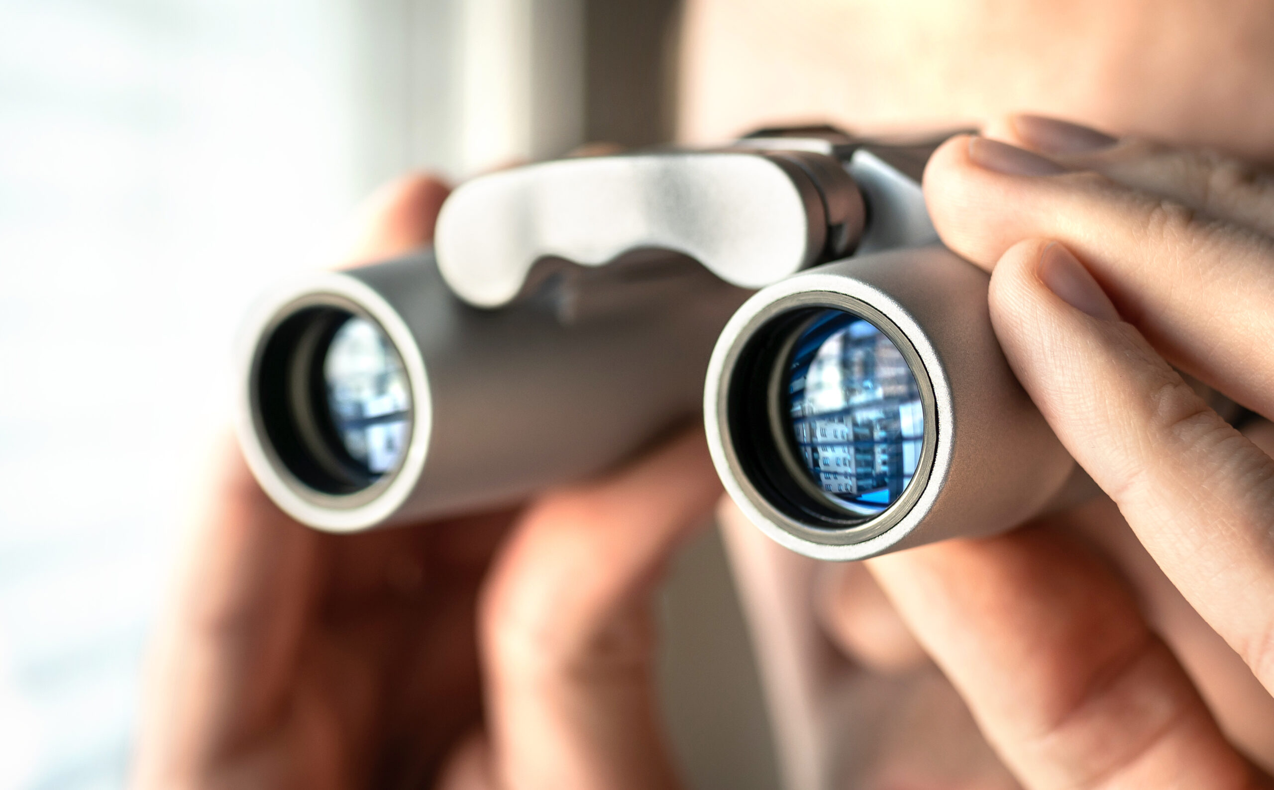 Man watching out the window with binoculars. Curious and nosy ne