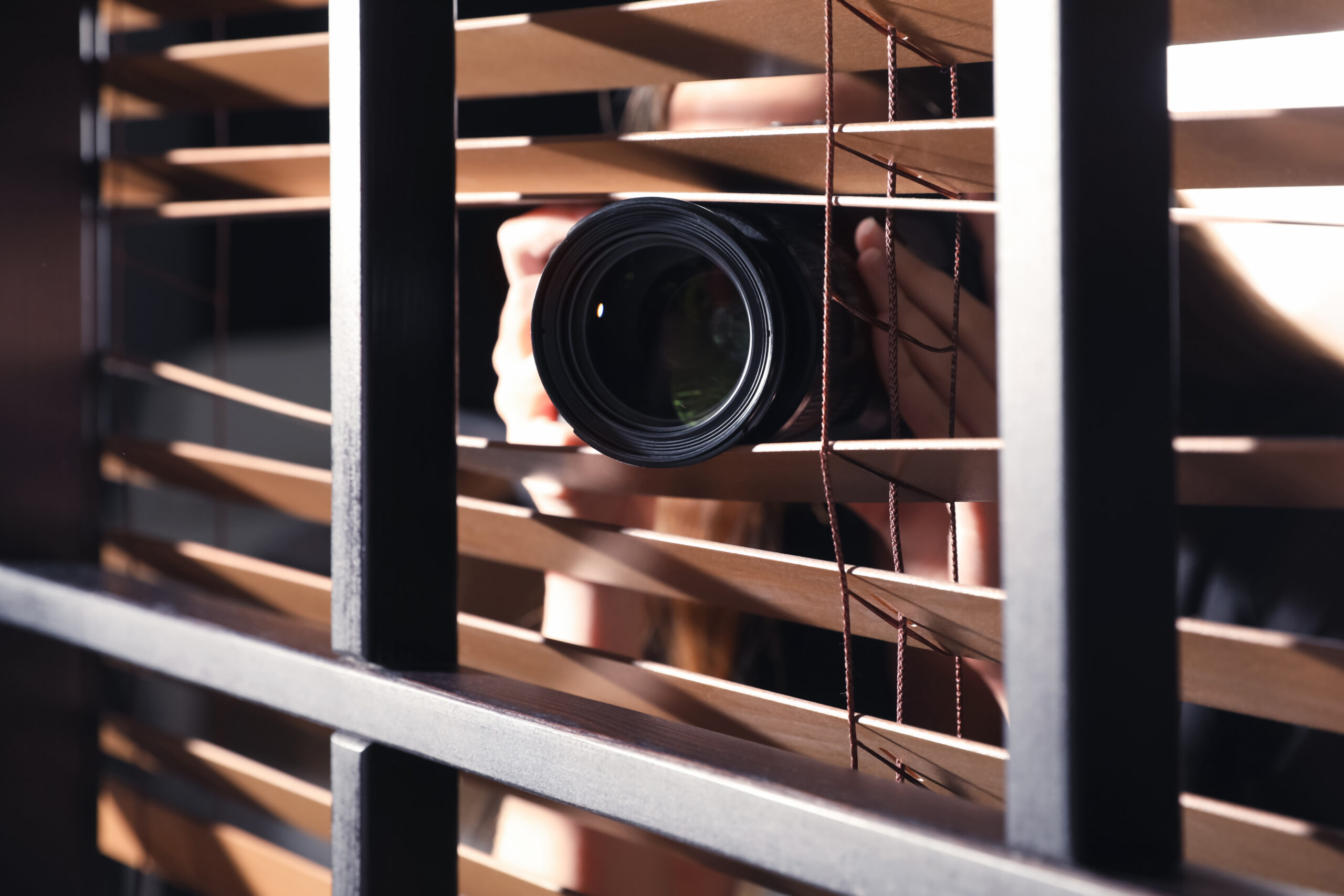 Private detective with camera spying near window indoors, closeu